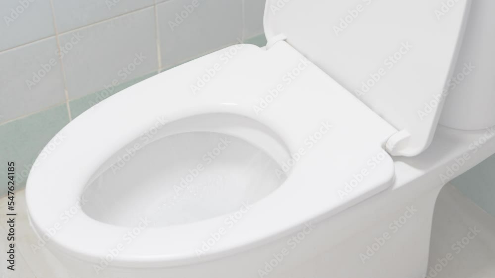 flushing water in white toilet bowl