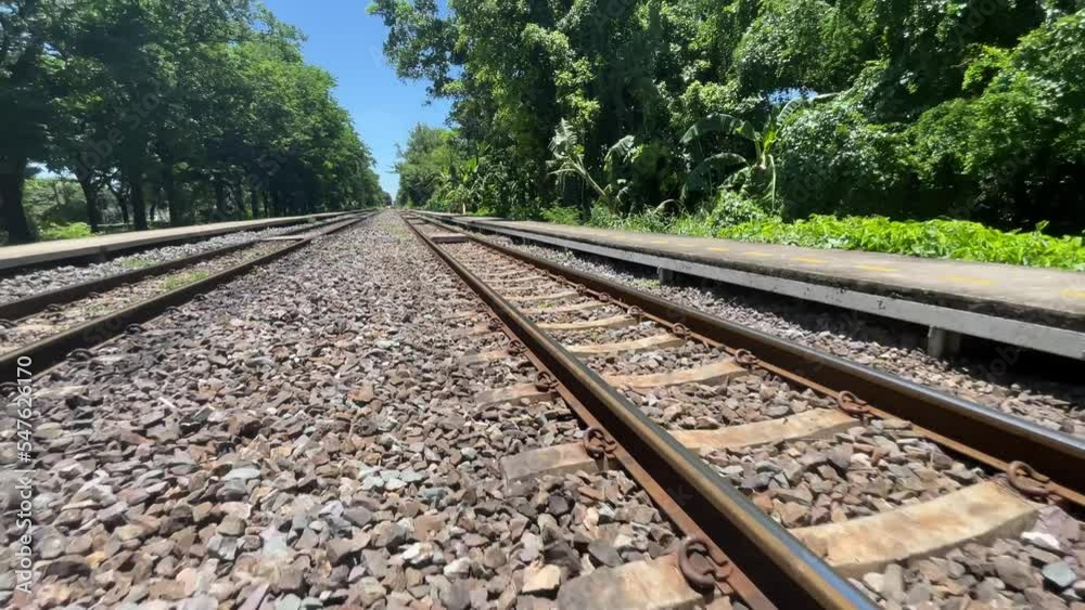 BANGKOK, THAILAND - Train track view with crushed stone with blue sky and trees. Moving train on a sunny day