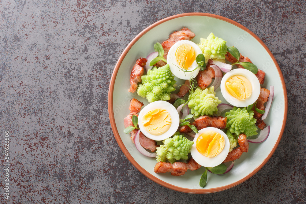 Delicious salad of romanesco broccoli, boiled eggs, fried bacon and fresh microgreen close-up in a plate on the table. Horizontal top view from above Delicious salad of romanesco broccoli, boiled eggs, fried bacon and fresh microgreen close-up in a plate on the table. Horizontal top view from above