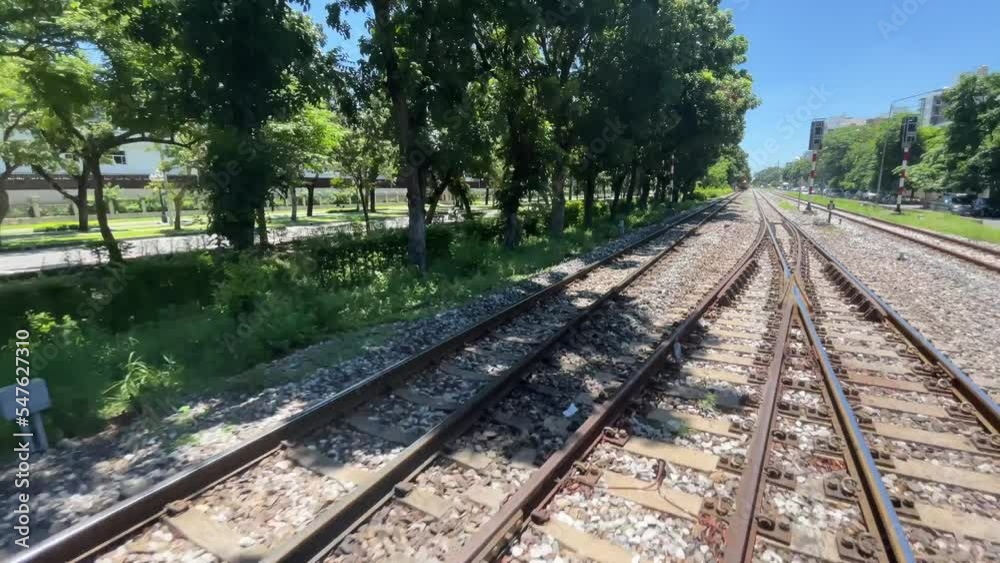 BANGKOK, THAILAND - POV riding on train with blue sky and trees. Moving train with train track view on a sunny day BANGKOK, THAILAND - POV riding on train with blue sky and trees. Moving train with train track view on a sunny day