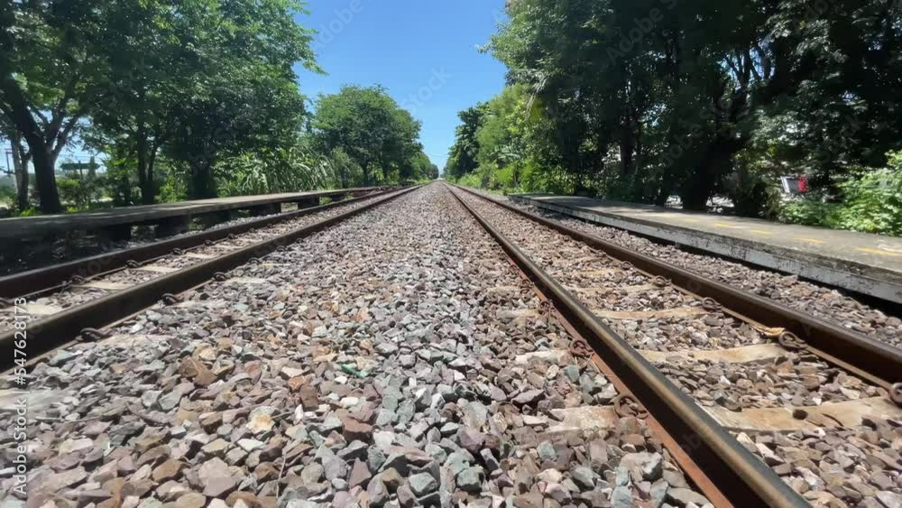 BANGKOK, THAILAND - Train track view with crushed stone with blue sky and trees. Moving train on a sunny day