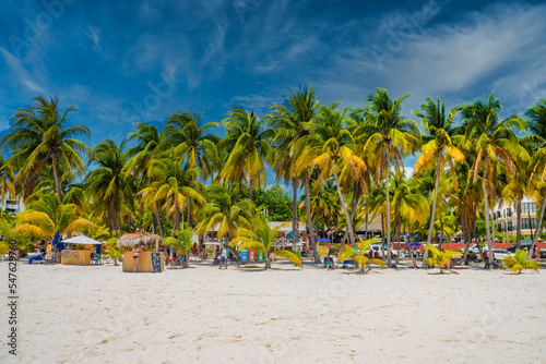 ISLA MUJERES ISLAND, MEXICO - APR 2022: Cocos beach bar on a beach with white sand and palms on a sunny day, Isla Mujeres island, Caribbean Sea, Cancun, Yucatan, Mexico