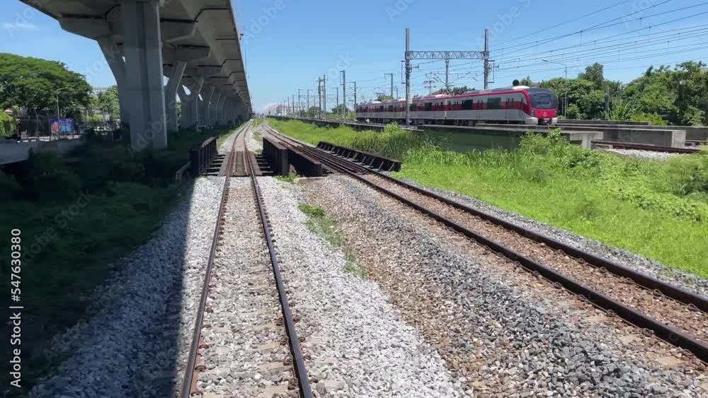 BANGKOK, THAILAND - POV riding on train with blue sky and trees. Moving train with train track view on a sunny day
