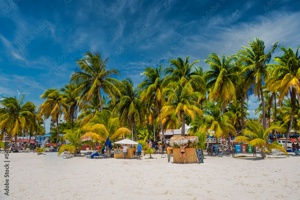 Fototapeta premium Cocos beach bar on a beach with white sand and palms on a sunny day, Isla Mujeres island, Caribbean Sea, Cancun, Yucatan, Mexico