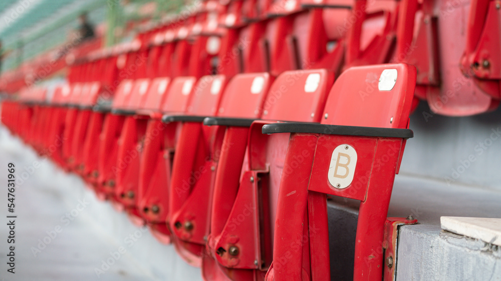 A row of red seating chair in VIP stand area at sport stadium, close-up and selective focus. Sport object background pattern photo. A row of red seating chair in VIP stand area at sport stadium, close-up and selective focus. Sport object background pattern photo.