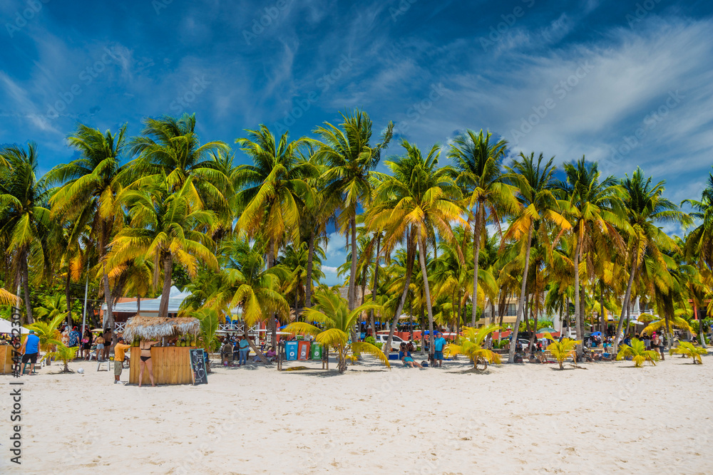 Fototapeta premium Cocos beach bar on a beach with white sand and palms on a sunny day, Isla Mujeres island, Caribbean Sea, Cancun, Yucatan, Mexico