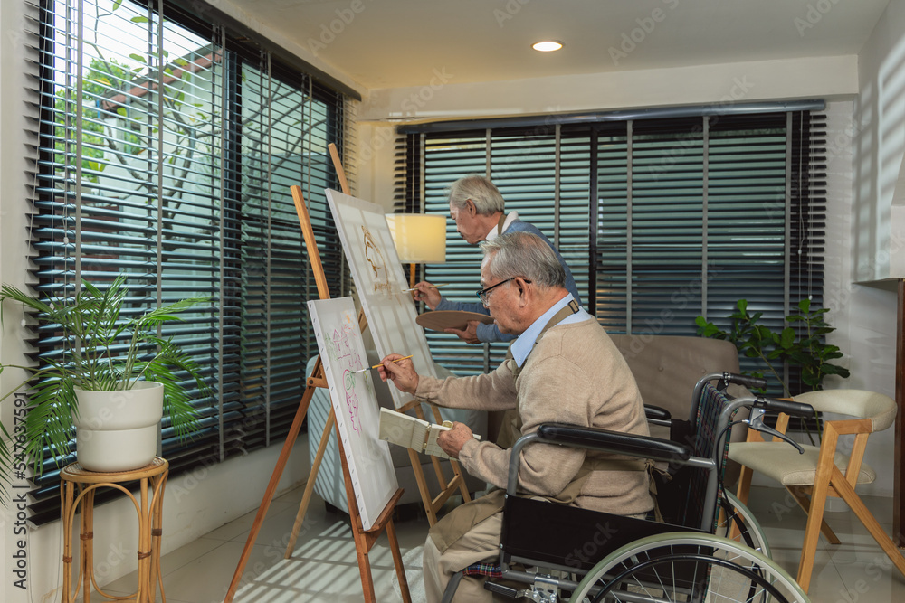 Elderly men ride a wheelchair doing hobby by painting at home