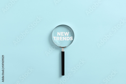 Magnifying glass magnifies the word new trends. Analyzing or searching for the new trends