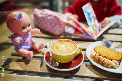 Adorable preschooler girl drawing in cafe while her mother is drinking coffee