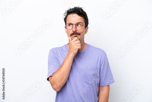 Young man with moustache isolated on white background having doubts and thinking