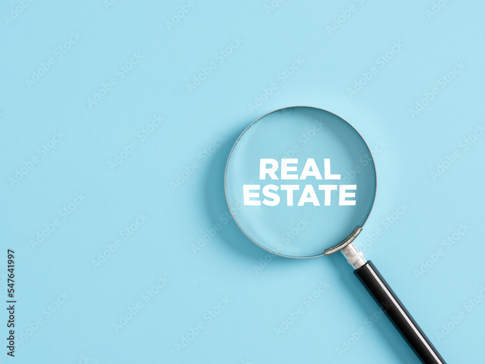 Magnifier with the text real estate on blue background. Real estate search Magnifier with the text real estate on blue background. Real estate search