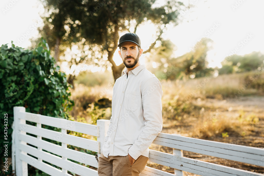 Fototapeta premium Portrait of a young bearded man wearing a black cap at countryside
