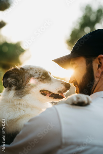 Portrait of a young bearded man wearing a black cap, with his dog, at countryside