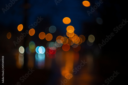 Fototapeta Naklejka Na Ścianę i Meble -  Blurred view of city street with lights at winter rainy night. Bokeh lights background. Abstract artistic photography.