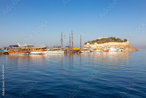 Boats at Marina with Castle on the Coast in a Touristic Town by the Aegean Sea. Kusadasi, Turkey. Sunny Morning Sunrise.