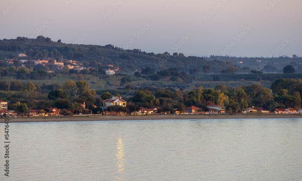 Fototapeta premium Residential Homes by the beach on Ionian Sea in a small touristic Town. Katakolo, Greece. Twilight Sunrise Sky.