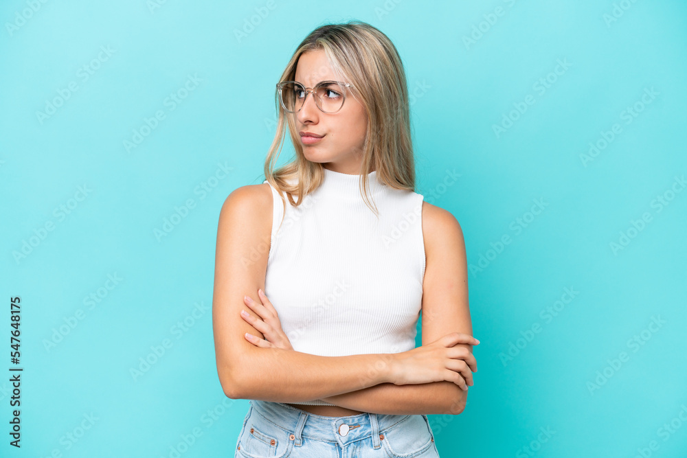 Young caucasian woman isolated on blue background keeping the arms crossed Young caucasian woman isolated on blue background keeping the arms crossed