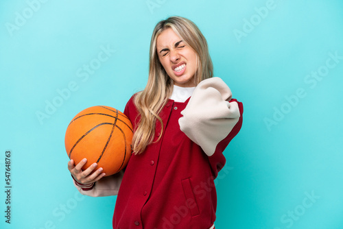 Young caucasian basketball player woman isolated on blue background suffering from pain in shoulder for having made an effort