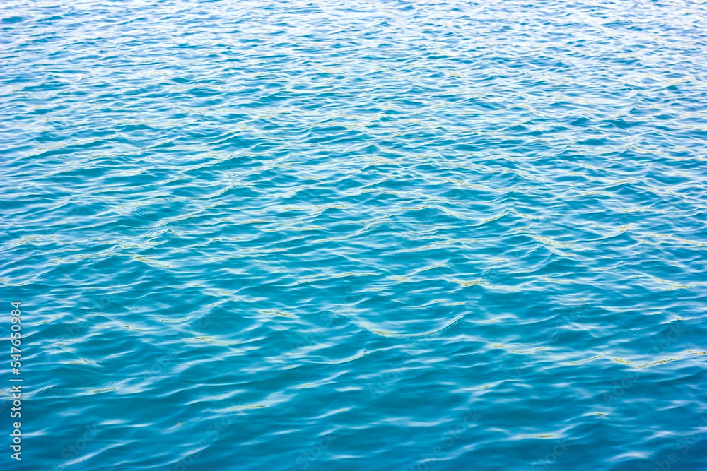 Light blue and turquoise sea water surface with waves texture in summer.