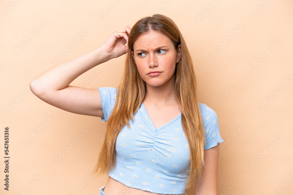 Young caucasian woman isolated on beige background having doubts while scratching head
