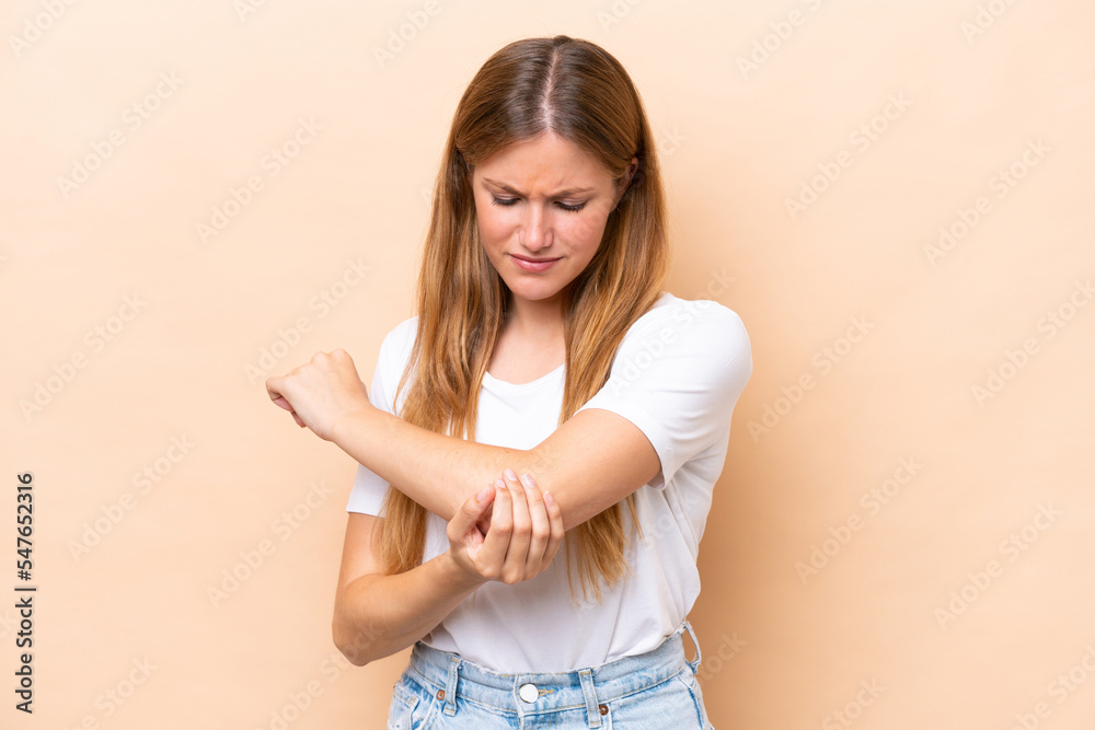Young caucasian woman isolated on beige background with pain in elbow Young caucasian woman isolated on beige background with pain in elbow