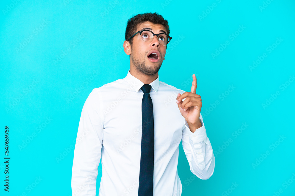 Young business Brazilian man isolated on blue background thinking an idea pointing the finger up Young business Brazilian man isolated on blue background thinking an idea pointing the finger up