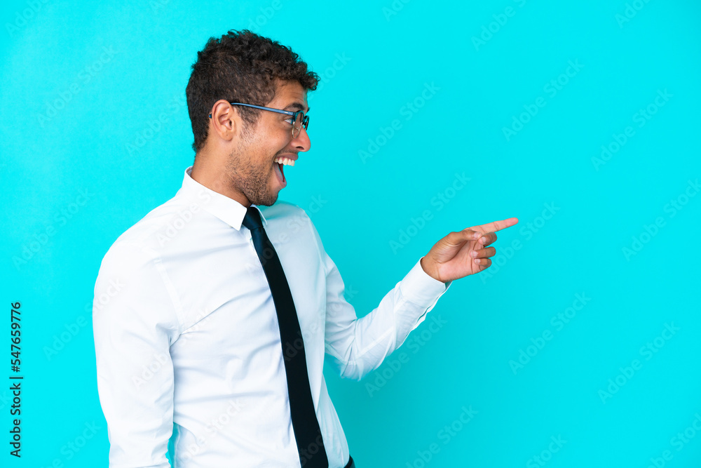 Young business Brazilian man isolated on blue background pointing finger to the side and presenting a product