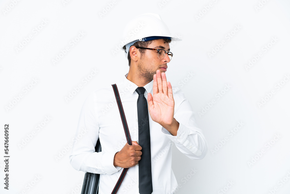 Architect brazilian man with helmet and holding blueprints making stop gesture and disappointed Architect brazilian man with helmet and holding blueprints making stop gesture and disappointed