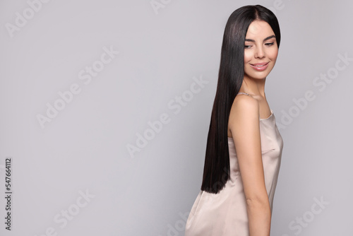 Portrait of beautiful young woman with healthy strong hair on light grey background, space for text