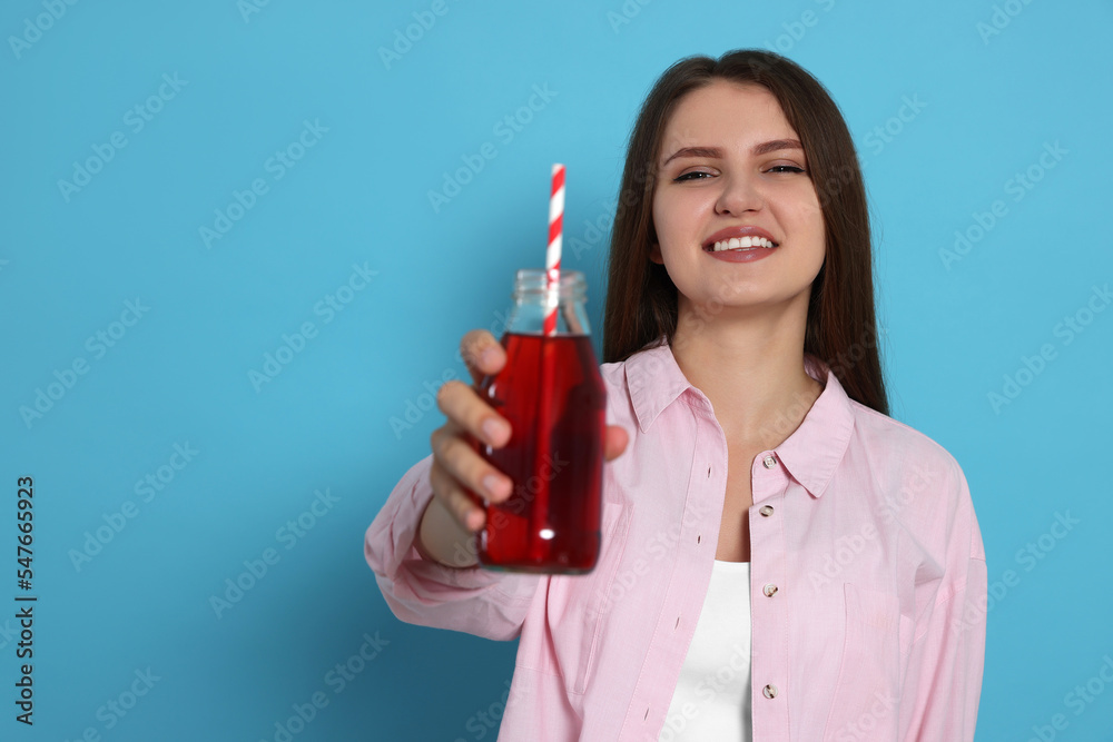 Beautiful young woman with glass bottle of juice on light blue background. Space for text Beautiful young woman with glass bottle of juice on light blue background. Space for text