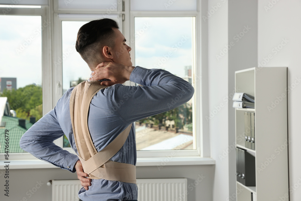 Young man with orthopedic corset in room Young man with orthopedic corset in room