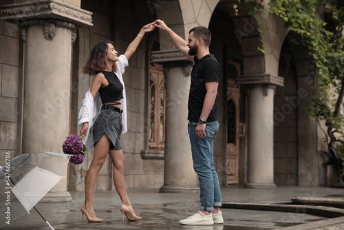 Young couple dancing under rain on city street
