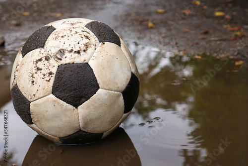 Dirty soccer ball in muddy puddle  space for text