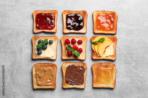 Tasty toasts with different spreads and fruits on light grey table, flat lay