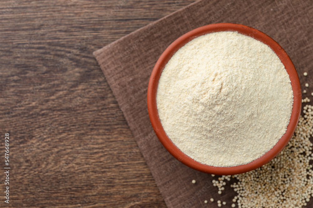 Quinoa flour in bowl and seeds on wooden table, top view. Space for text Quinoa flour in bowl and seeds on wooden table, top view. Space for text