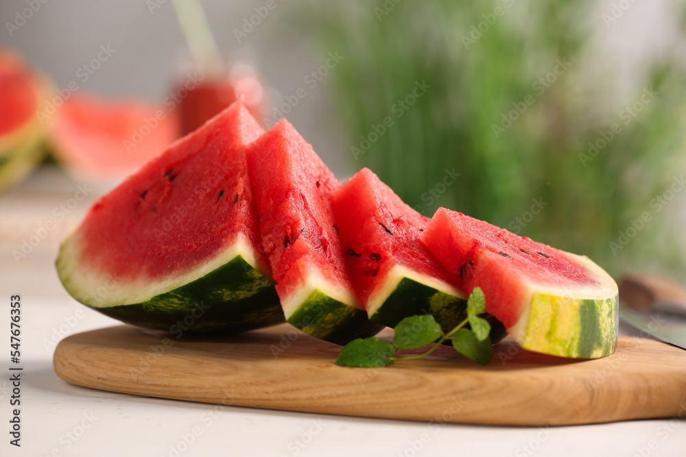 Slices of delicious ripe watermelon with mint on white wooden table indoors, closeup