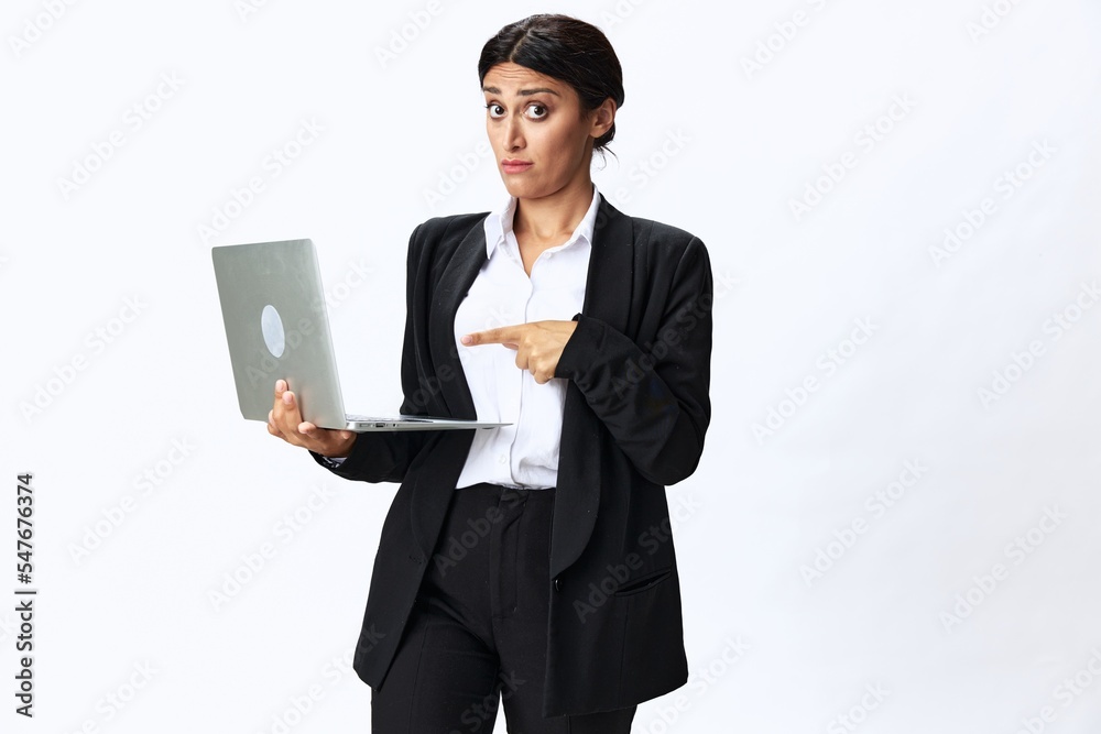 Business woman with laptop in hand in black business suit shows signals gestures and emotions on white background, freelancer job online training Business woman with laptop in hand in black business suit shows signals gestures and emotions on white background, freelancer job online training