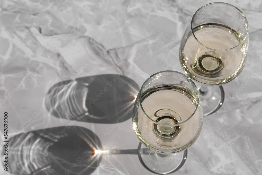 Glasses of white wine served on grey marble table, above view. Space for text Glasses of white wine served on grey marble table, above view. Space for text