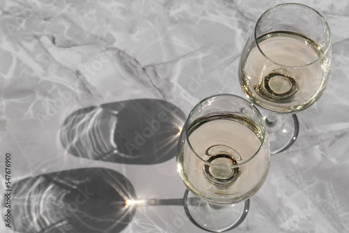 Glasses of white wine served on grey marble table, above view. Space for text