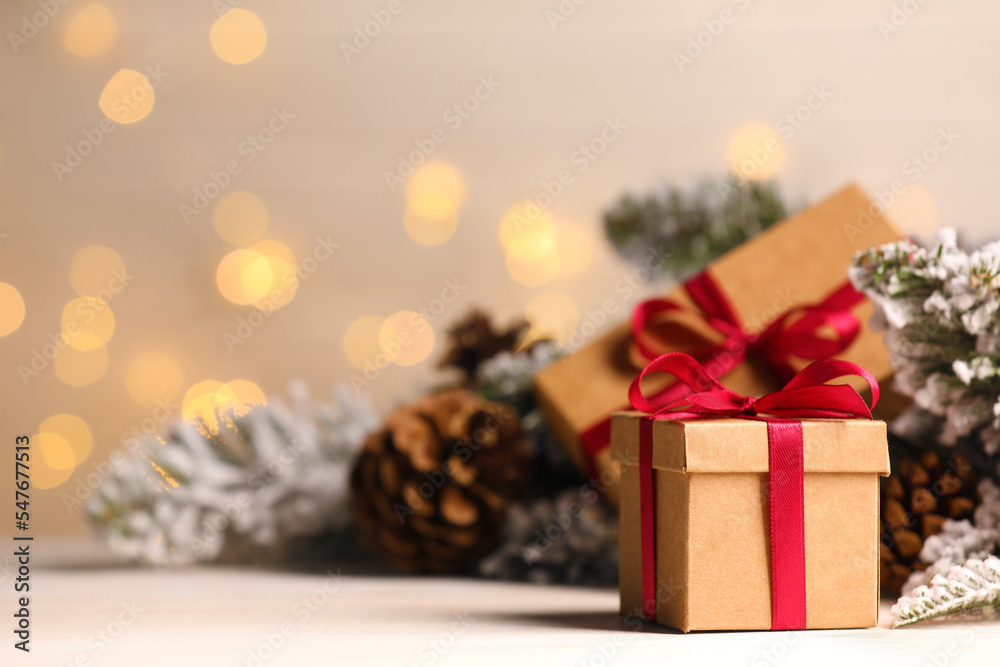 Gift boxes and Christmas decor on wooden table against blurred festive lights, space for text