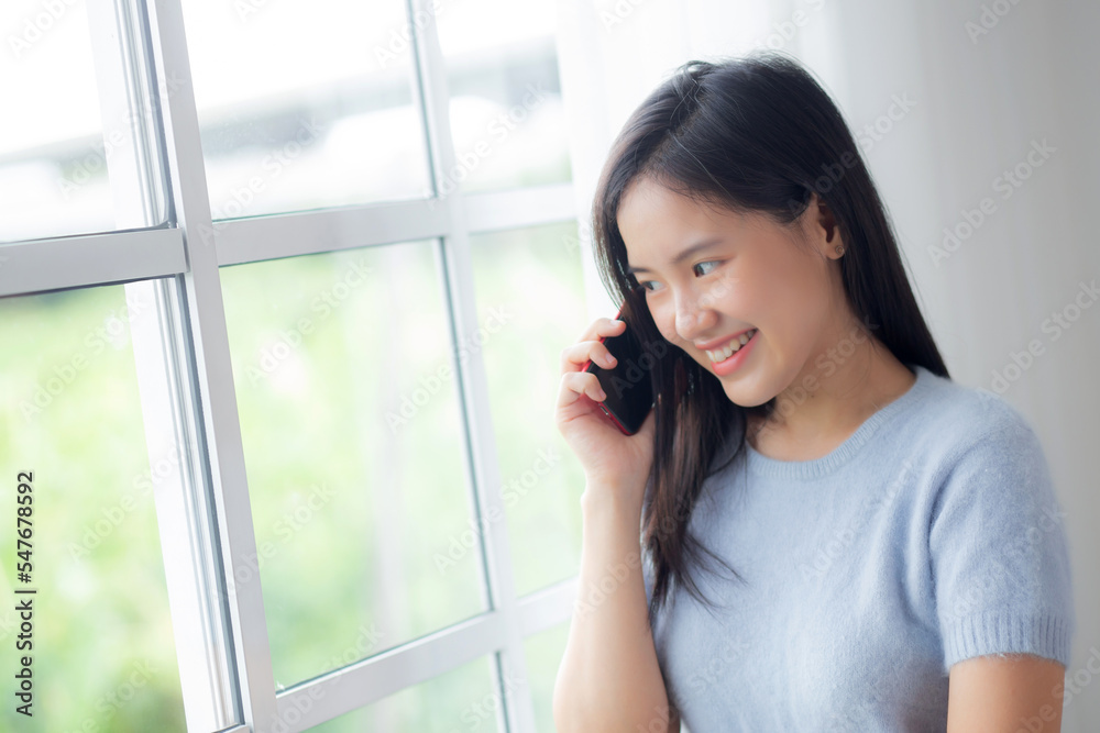 Happiness young asian woman talking with smartphone in the living room at home, female smiling and speaking with smart phone while relax and cozy at home, lifestyles and communication concept. Happiness young asian woman talking with smartphone in the living room at home, female smiling and speaking with smart phone while relax and cozy at home, lifestyles and communication concept.