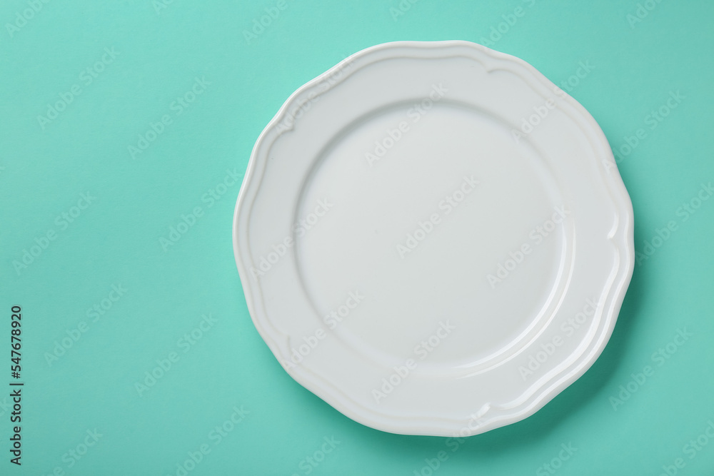Empty white ceramic plate on turquoise background, top view. Space for text - obrazy, fototapety, plakaty 