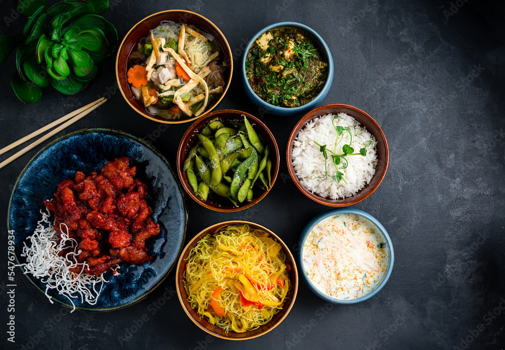 Asian food set rice noodles with red pepper, sweet and sour chicken, chicken noodle soup with mushrooms, creamy soup with salmon, beans, homemade cheese with spinach and spices, rice.