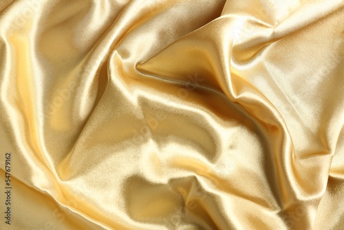Golden shiny fabric as background, top view