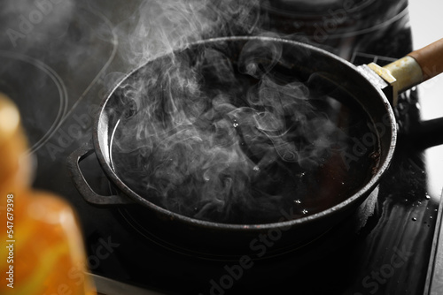 Cuadro en lienzo Frying pan with hot used cooking oil on stove