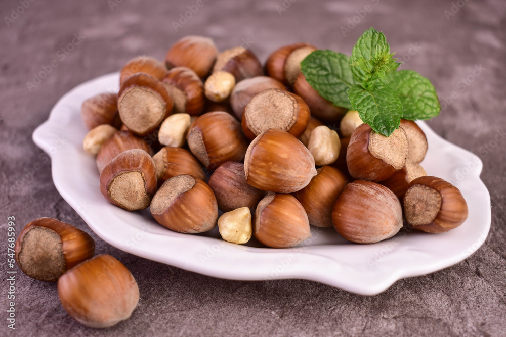 Hazelnuts in a porcelain plate on a gray background. Close-up.
Hazelnuts in a porcelain plate on a gray background. Close-up.
