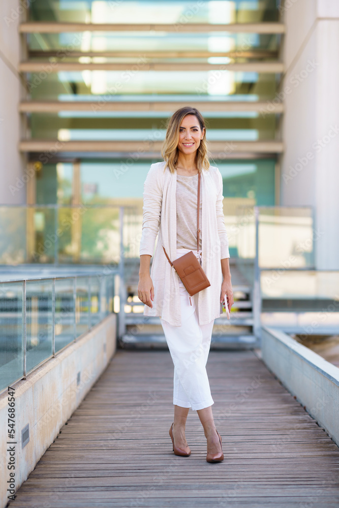 Obraz premium Stylish woman on footbridge outside modern building