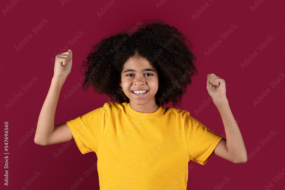 Positive african american girl raising fists up and smiling Positive african american girl raising fists up and smiling