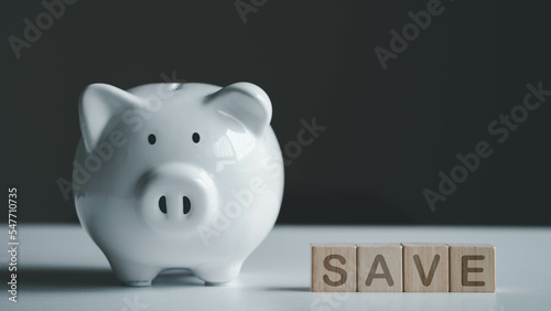 Money saving and finance concept. White piggy bank and wood cube with SAVE wording on white table and copy space. Save for education, investment and loan. 