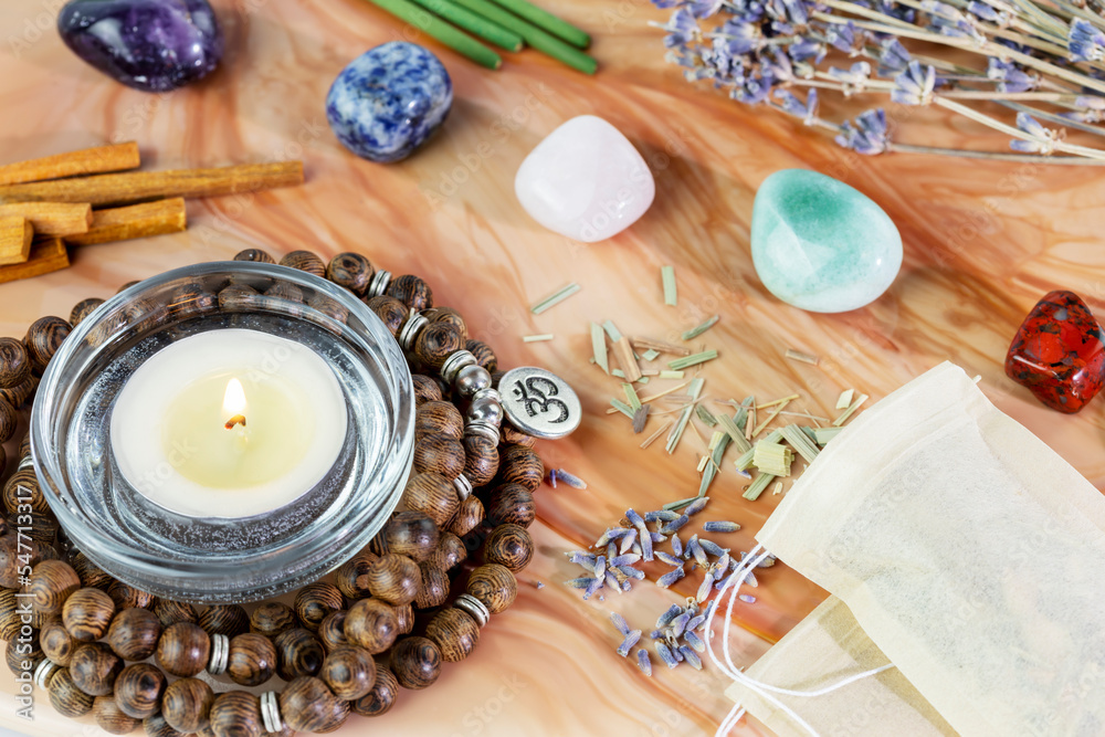 Fototapeta premium Self-care, healing composition with rosary beads, aroma sticks, chakra stones, sandalwood sticks and candle on a pink marble podium. Concept of relaxing at home, energy healing, meditation and me time